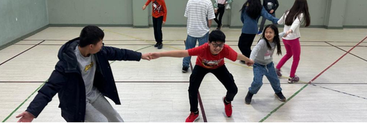 Children link hands to play a game in the gym.