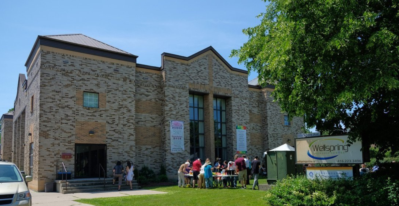 The Wellspring Worship Centre building, with a barbecue happening on the front lawn and people gathered to eat together