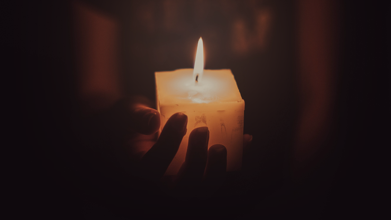 A hand holds a glowing candle