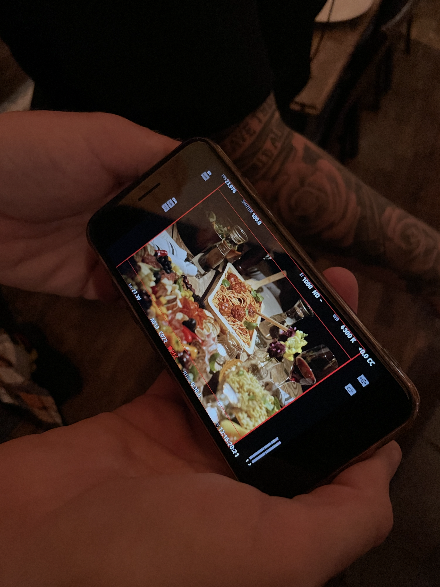 a behind the scenes look at a film being made with the film camera shot on an iphone showing a table food styled with a platter of meatballs and charcuterie