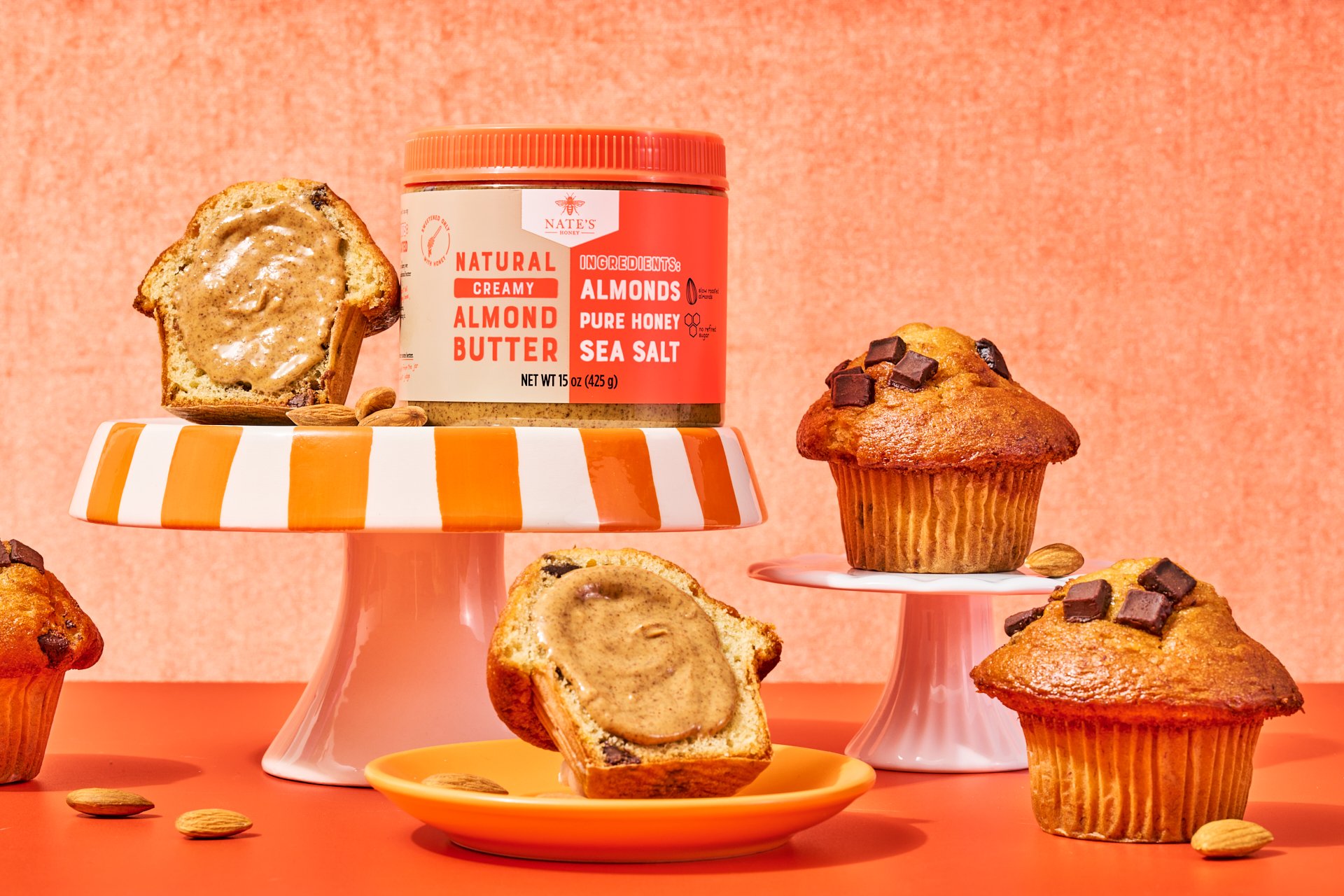 jar of almond butter with chocolate chip muffins on a pedestal