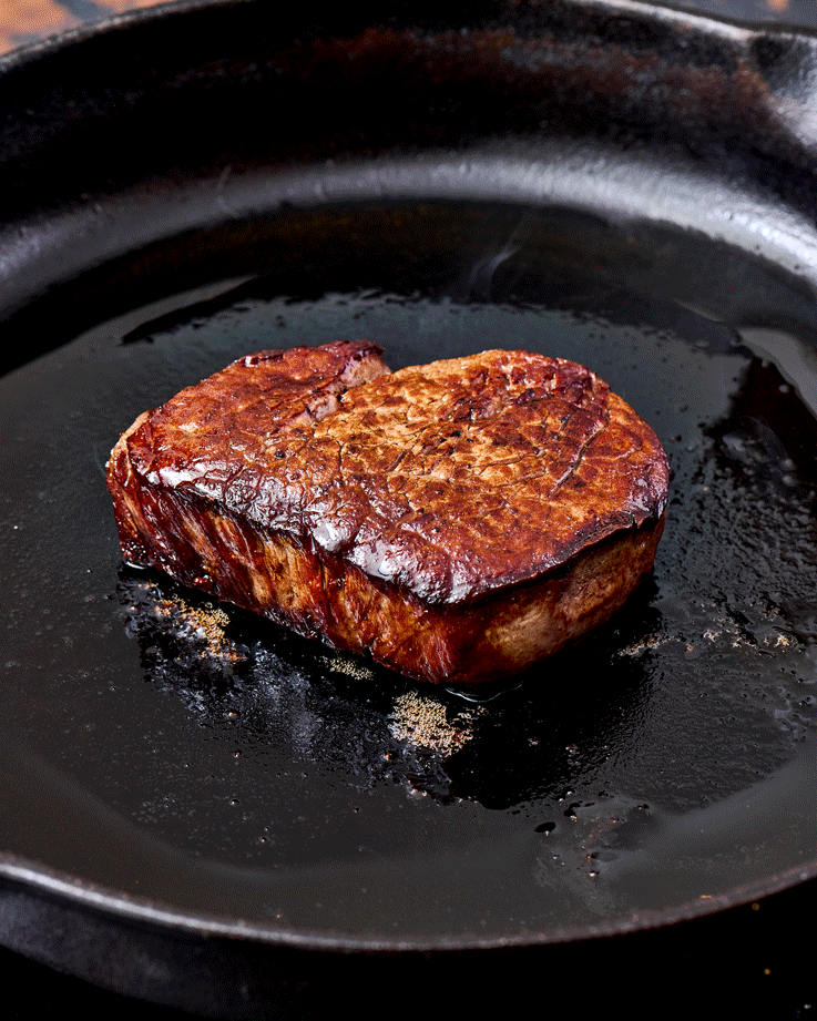dollop of butter melting on a steak in a cast iron pan