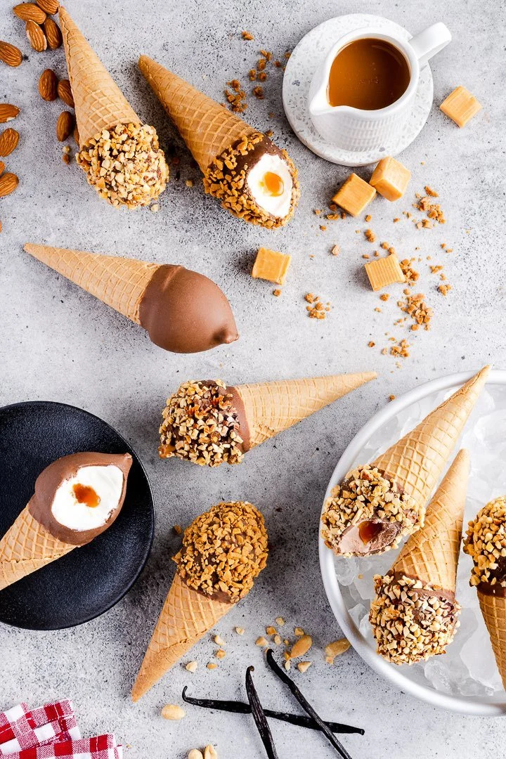 ice cream cones on a grey surface with pieces of caramel and skor bites