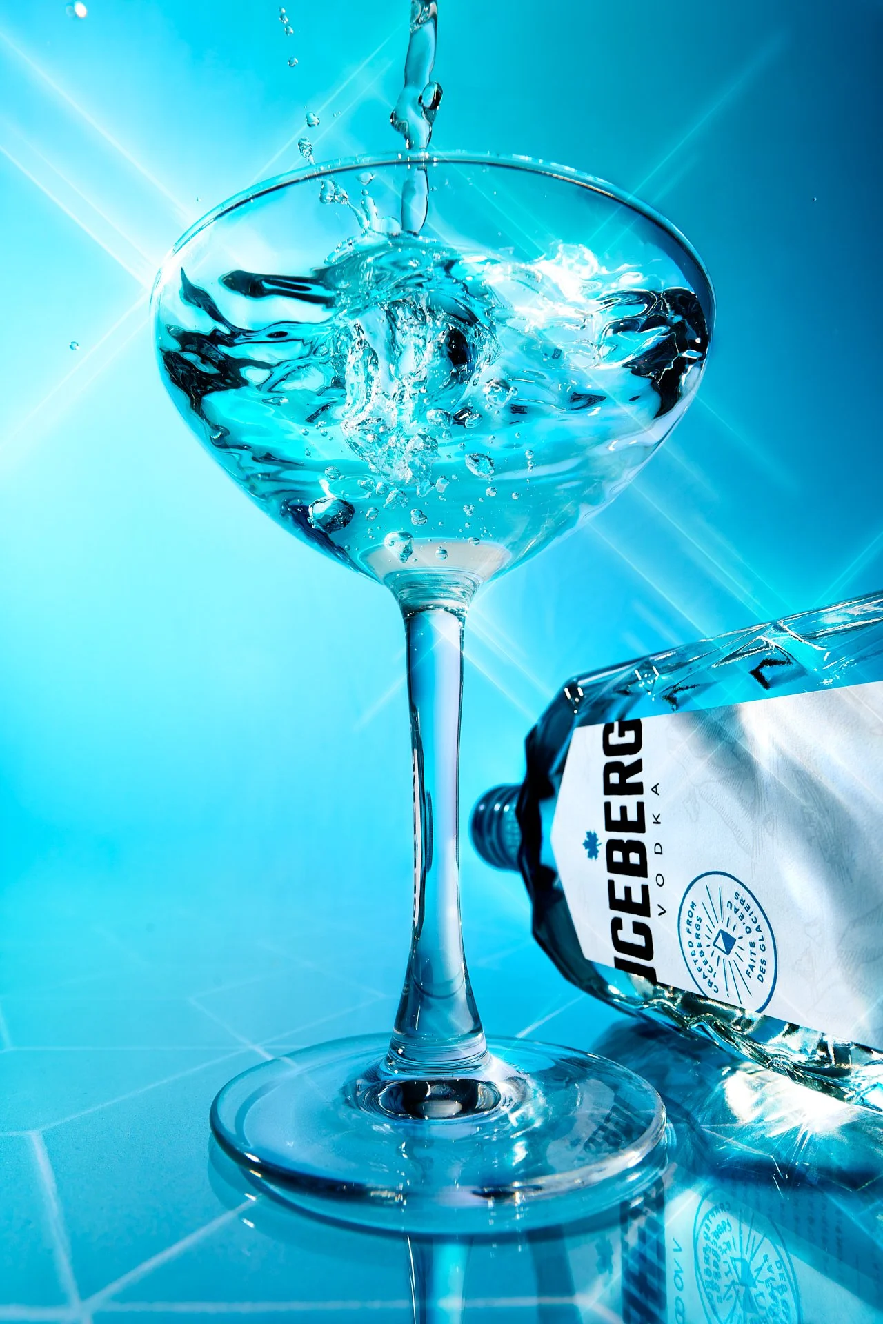 vodka glass and bottle against a bright blue background