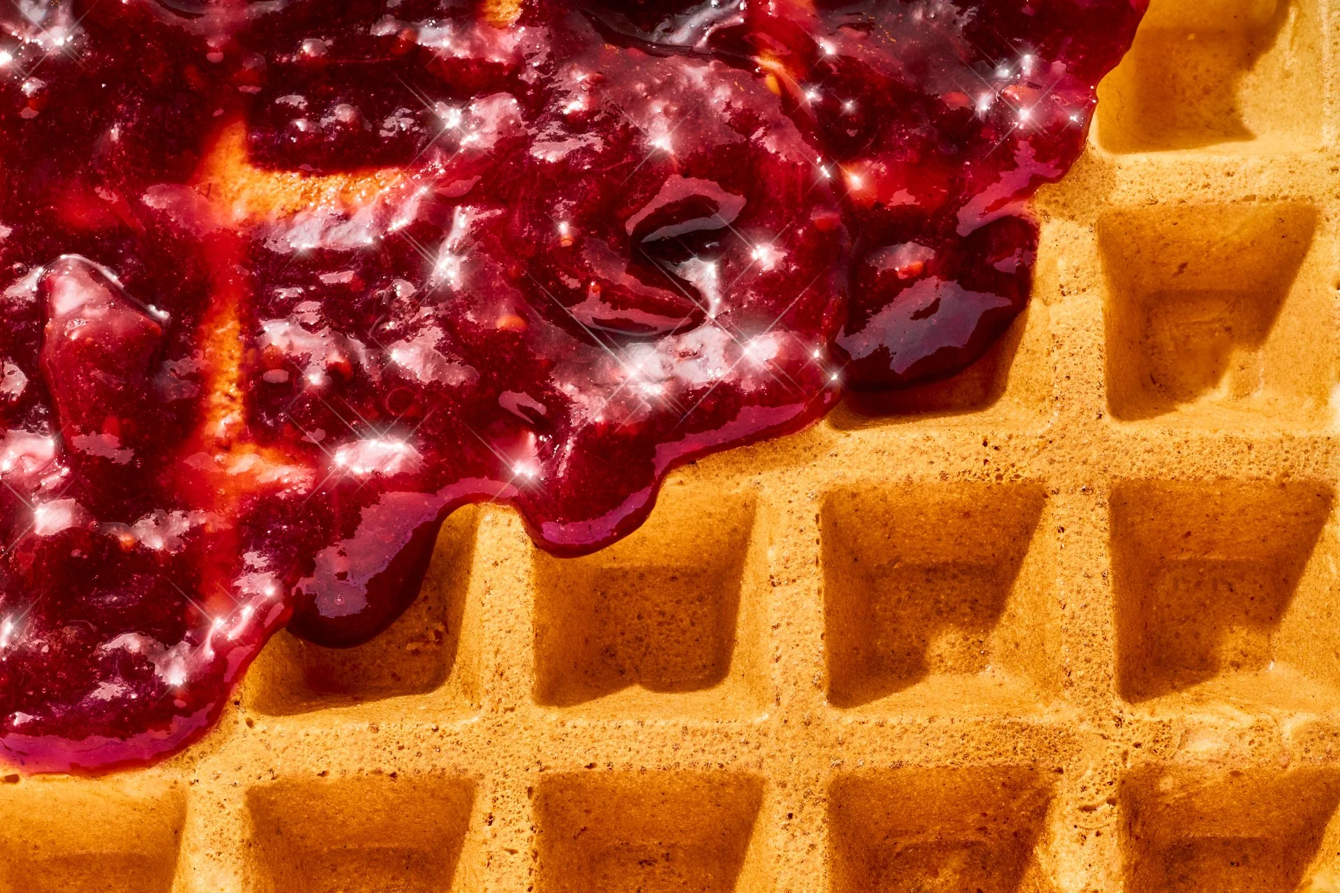 macro image of a waffle with cherry fruit spread dripping down with sunny studio lighting