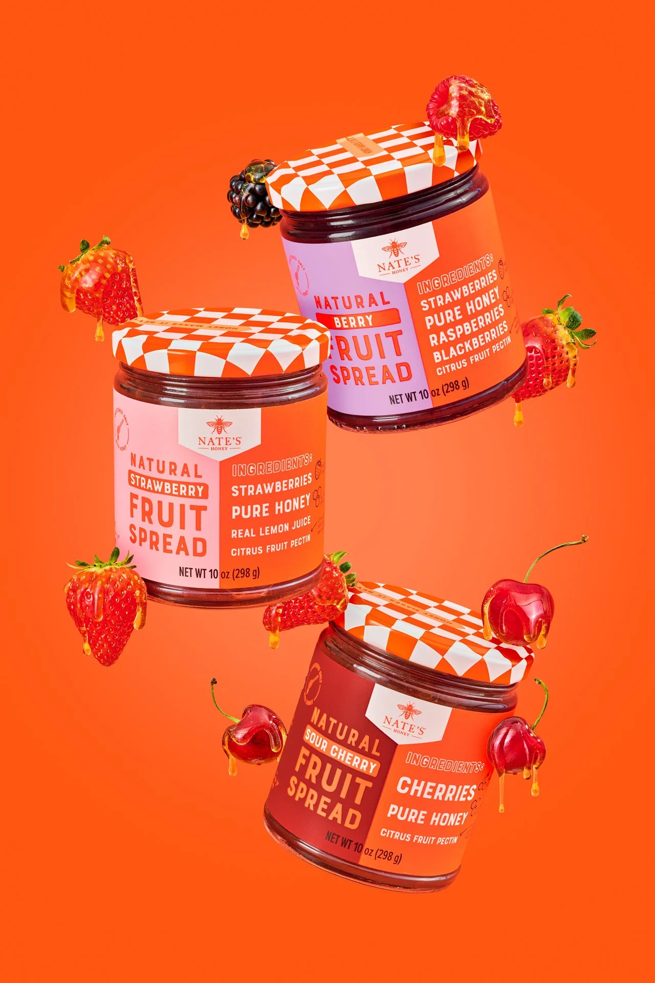 Creative commercial food photography featuring nate's honey fruit spread jars surrounded by fresh berries and fruit. flavors of cherry, mixed berrry and strawberry
