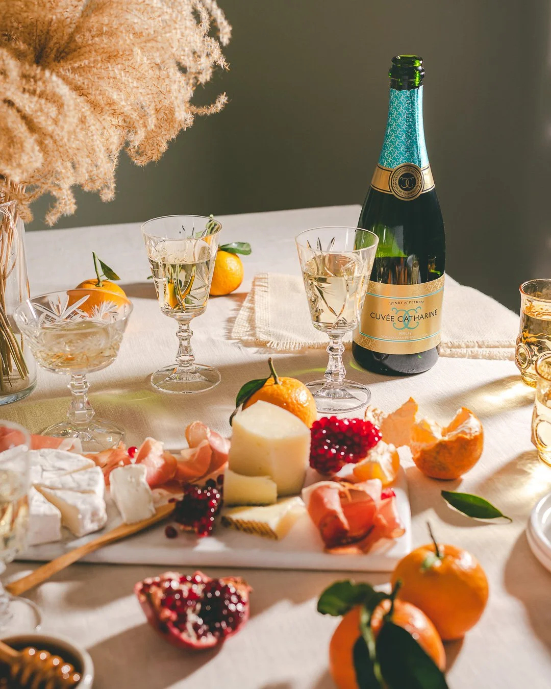 a tablescape with sprakling wine and winter season fruits with a cheese board