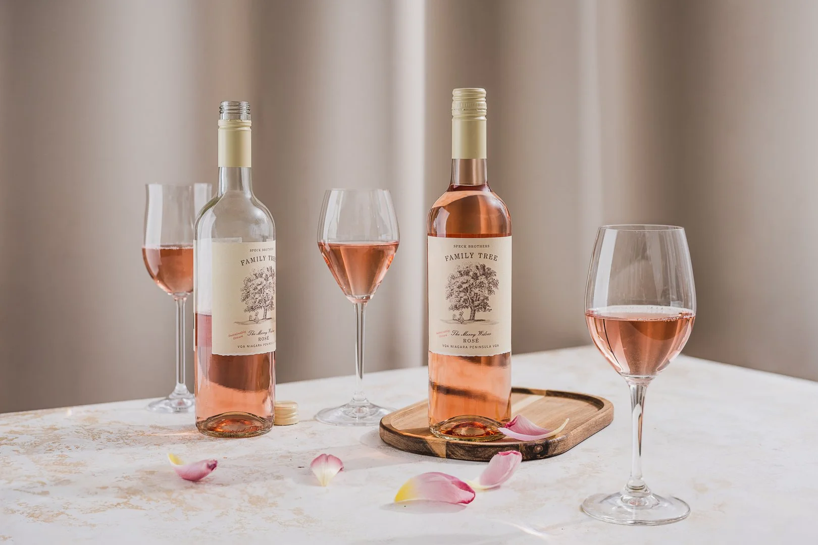 Commercial wine photography featuring speck bro's (henry of pelham) rosé wine bottles and a filled wine glass styled with delicate floral details.