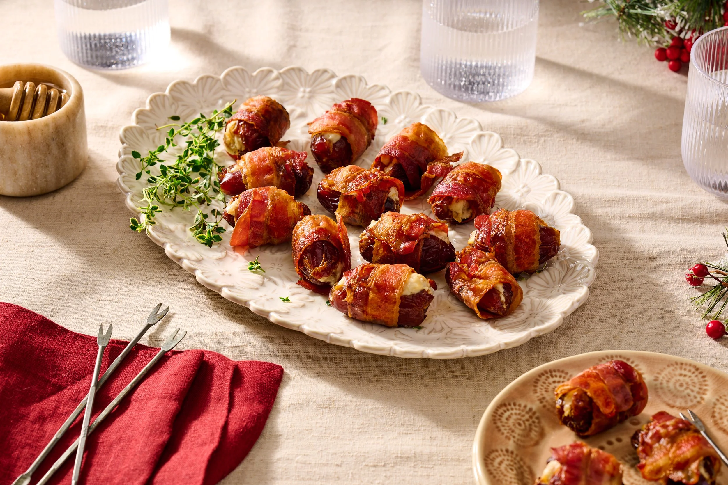 plate of bacon wrapped dates stuffed with goat cheese and walnuts in a festive season table seeting