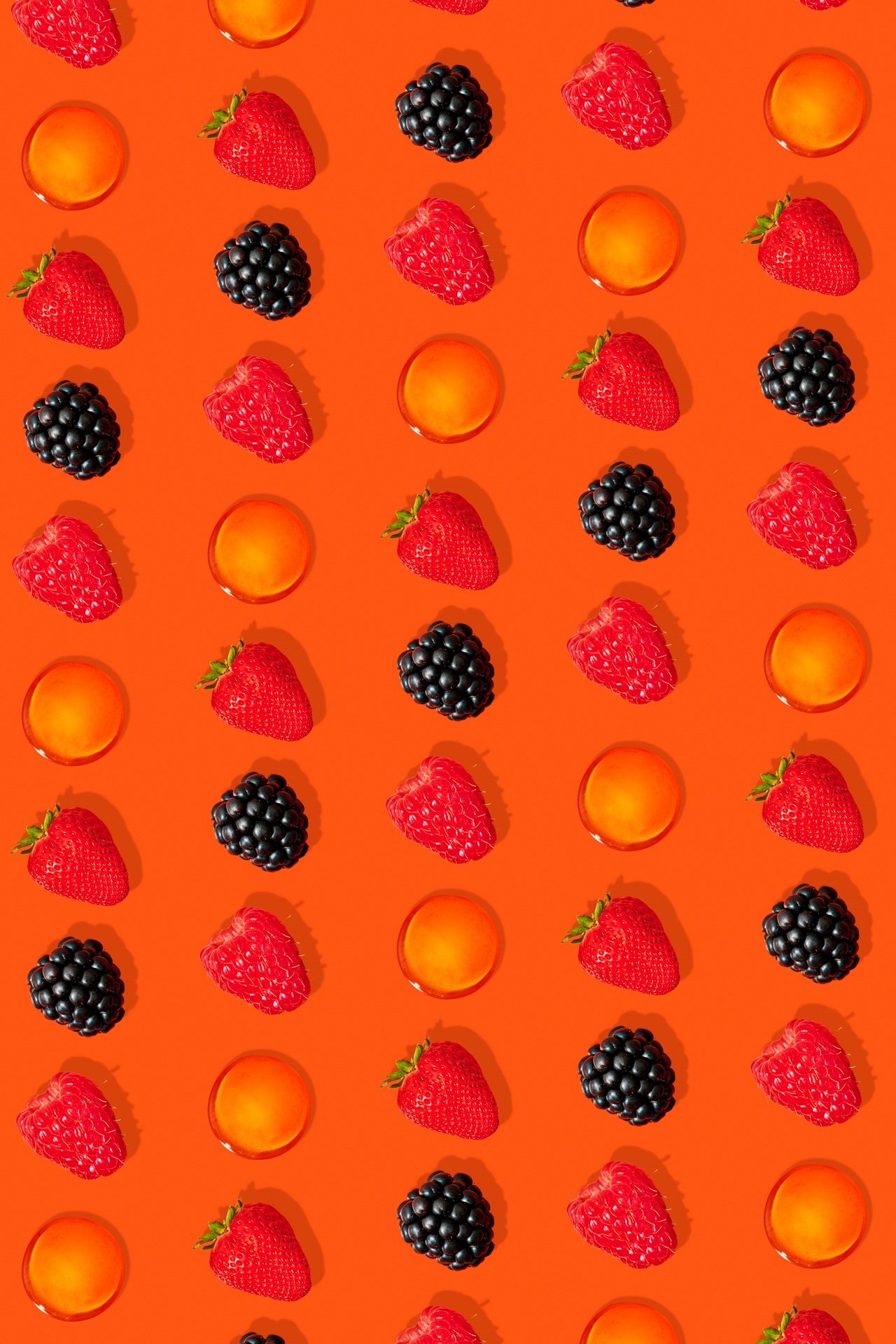 Pattern of strawberries, blackberries, orange fruit slices, on an orange background.