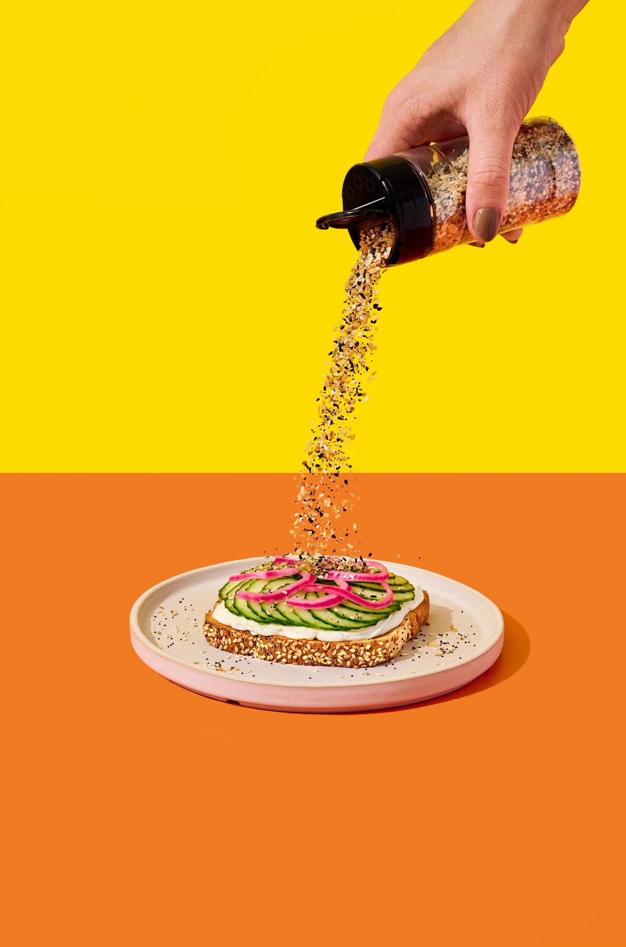 bold and colourful creative commercial food photography of everything bagel seasoning being sprinkled over a colourful toast with bread by country harvest
