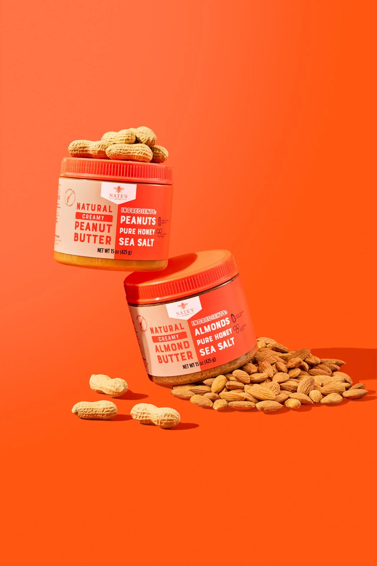 bold, colorful, vibrant commercial food photography of nut butter spread jars styled with peanuts and almond ingredients on a bright orange set.
