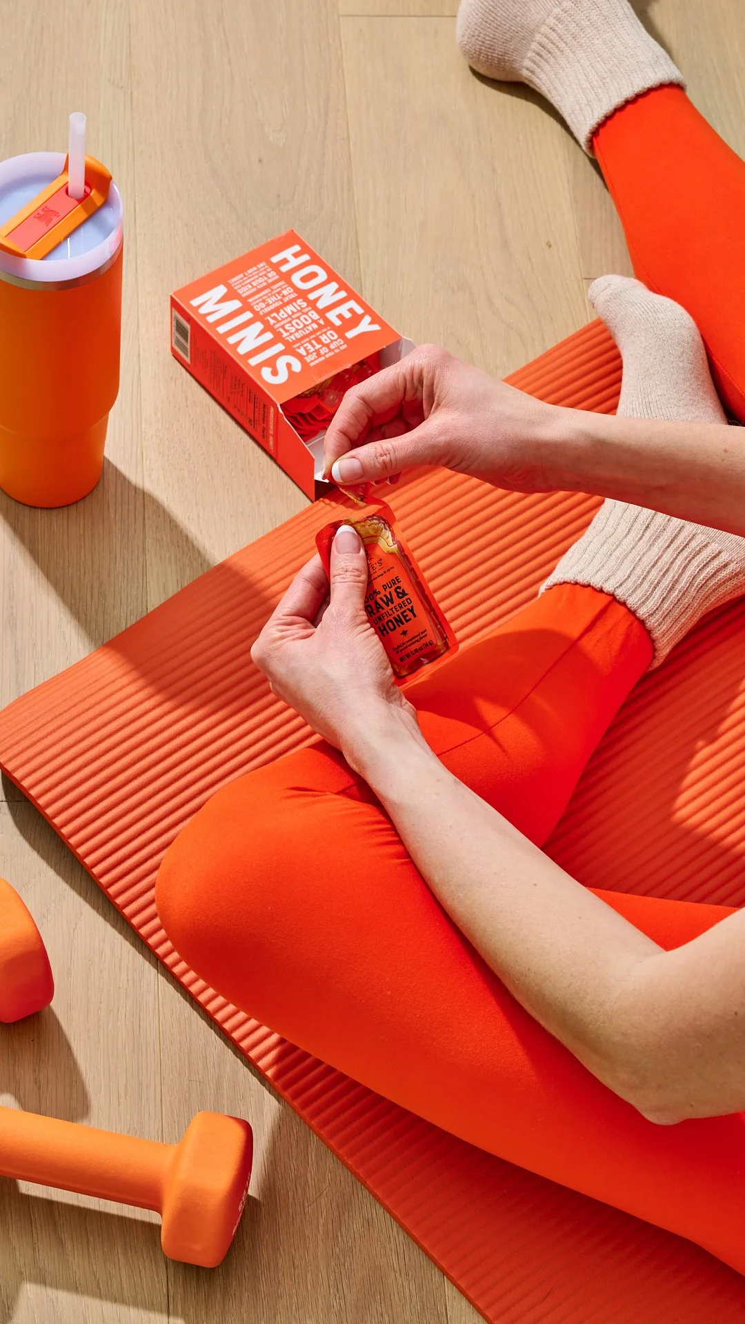 Lifestyle food photography featuring a nate's honey mini snack product being opened and enjoyed in a colourful workout setting. Product photography.
