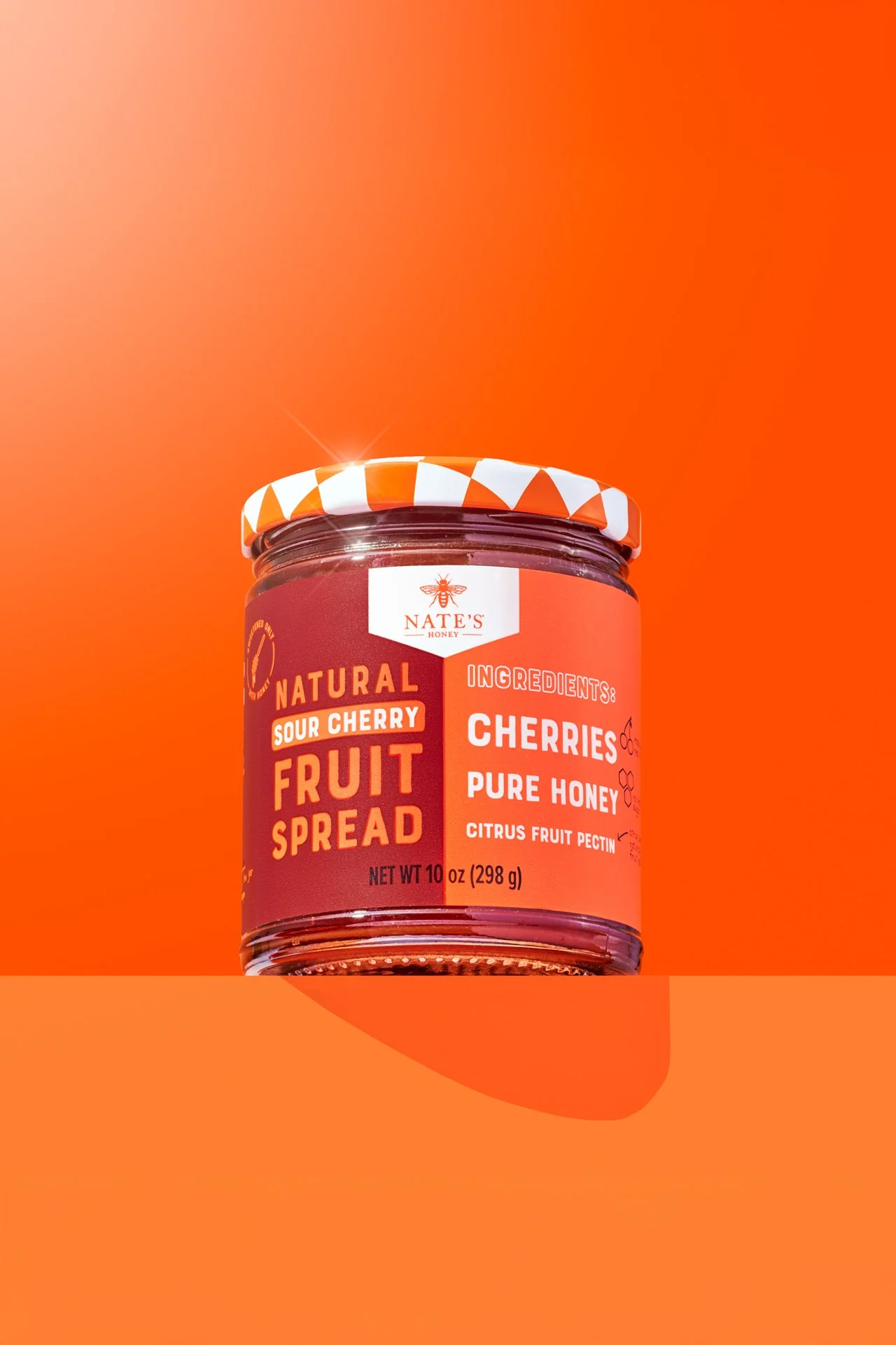 Commercial product photography of nate's honey cherry spread on a bright colourful set.
