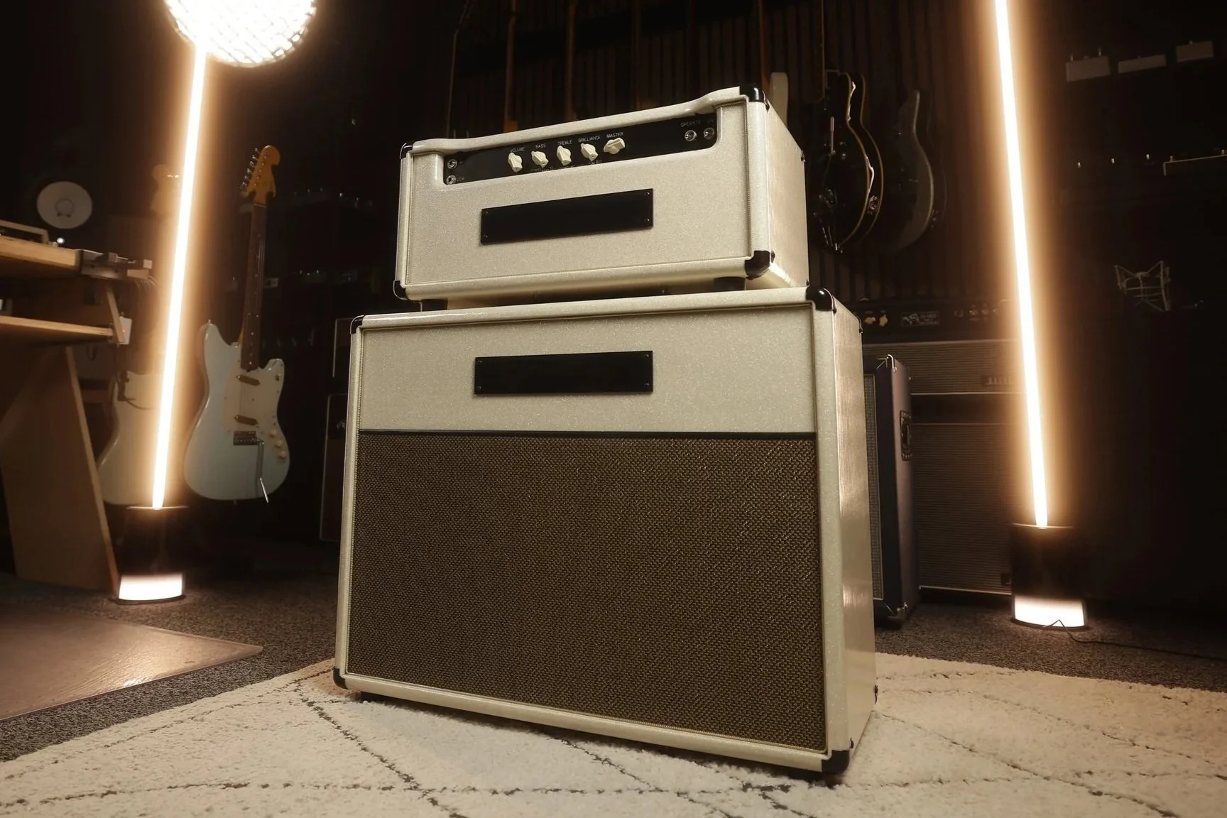 Matchless amplifier and speaker cabinet in music studio with guitars and audio equipment in the background.