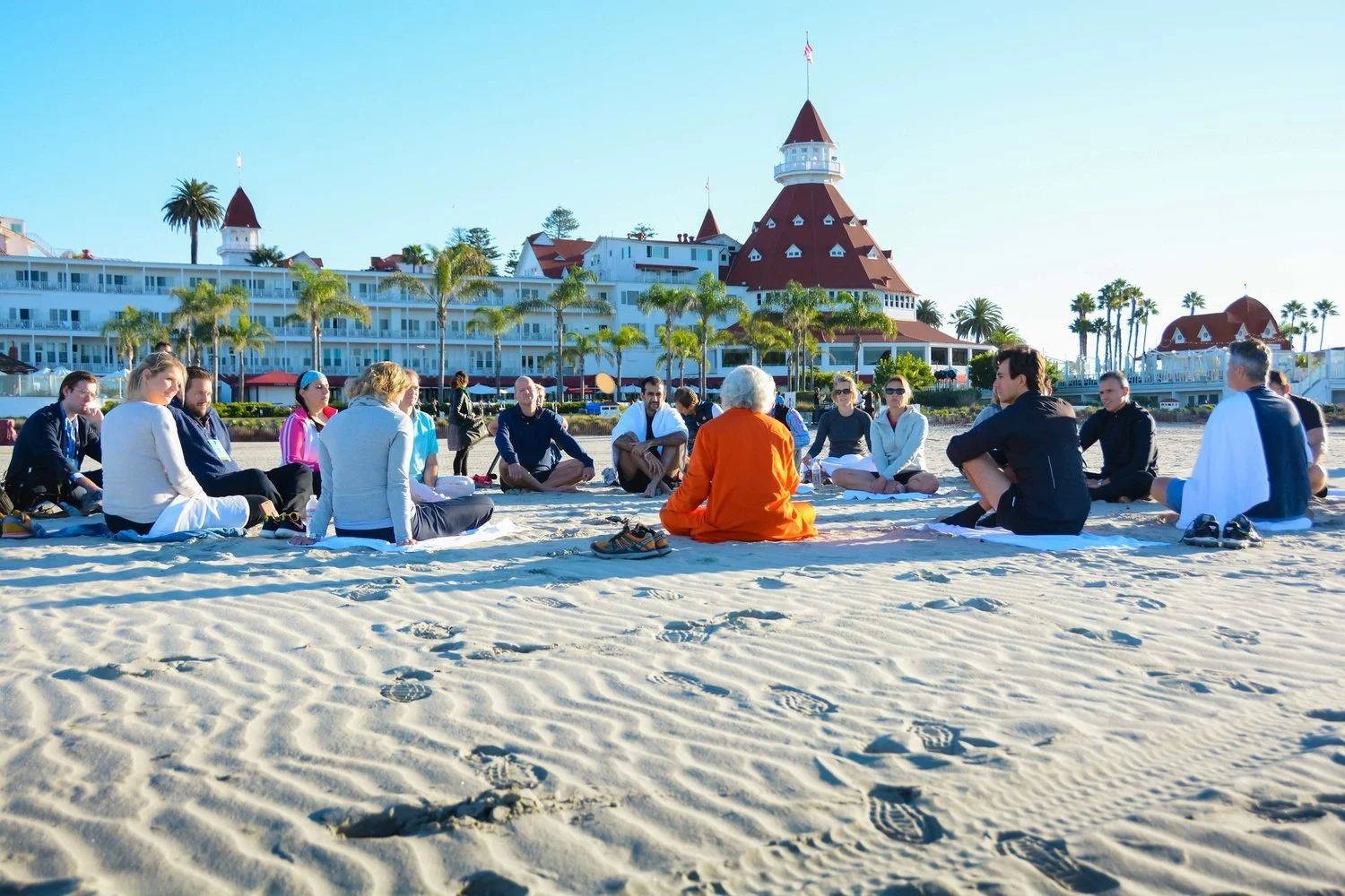 a group of conference goers participate in a guided meditation on the beach