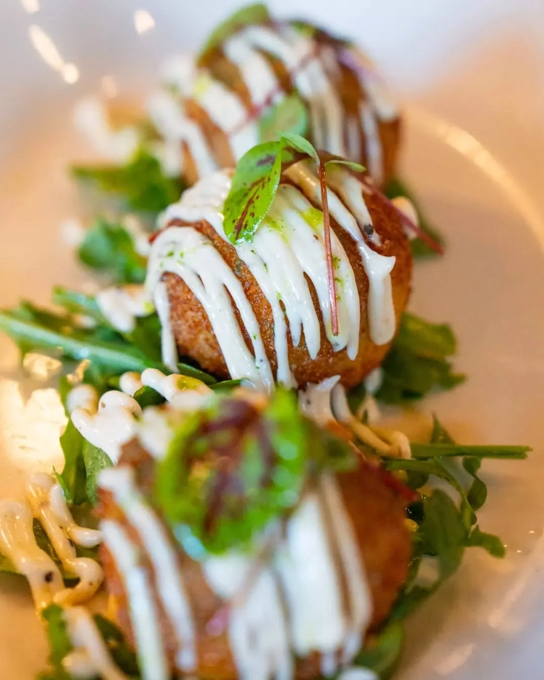 Arancini al Tartufo &ndash; golden and crispy outside, creamy risotto with mushrooms, pancetta, truffle &amp; sundried tomatoes inside. Served with rocket and our truffle mayo. A must-try starter