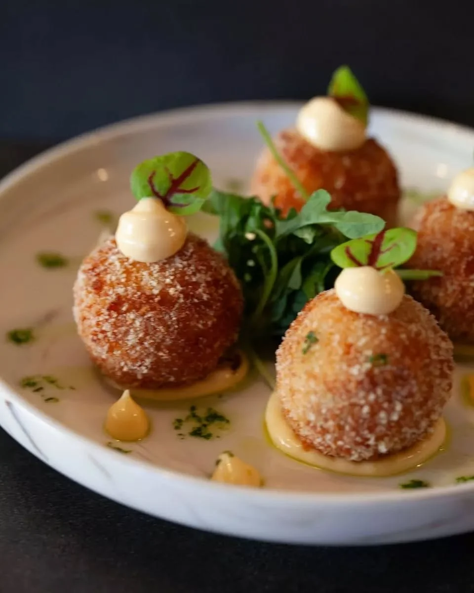 The perfect first bite at T&Aacute;VOLA 🤍🇮🇹

Golden Arancini ai Gamberi filled with prawns, scamorza, green peas, and lime mascarpone, made to be shared over good conversation and a glass of wine 🍷✨