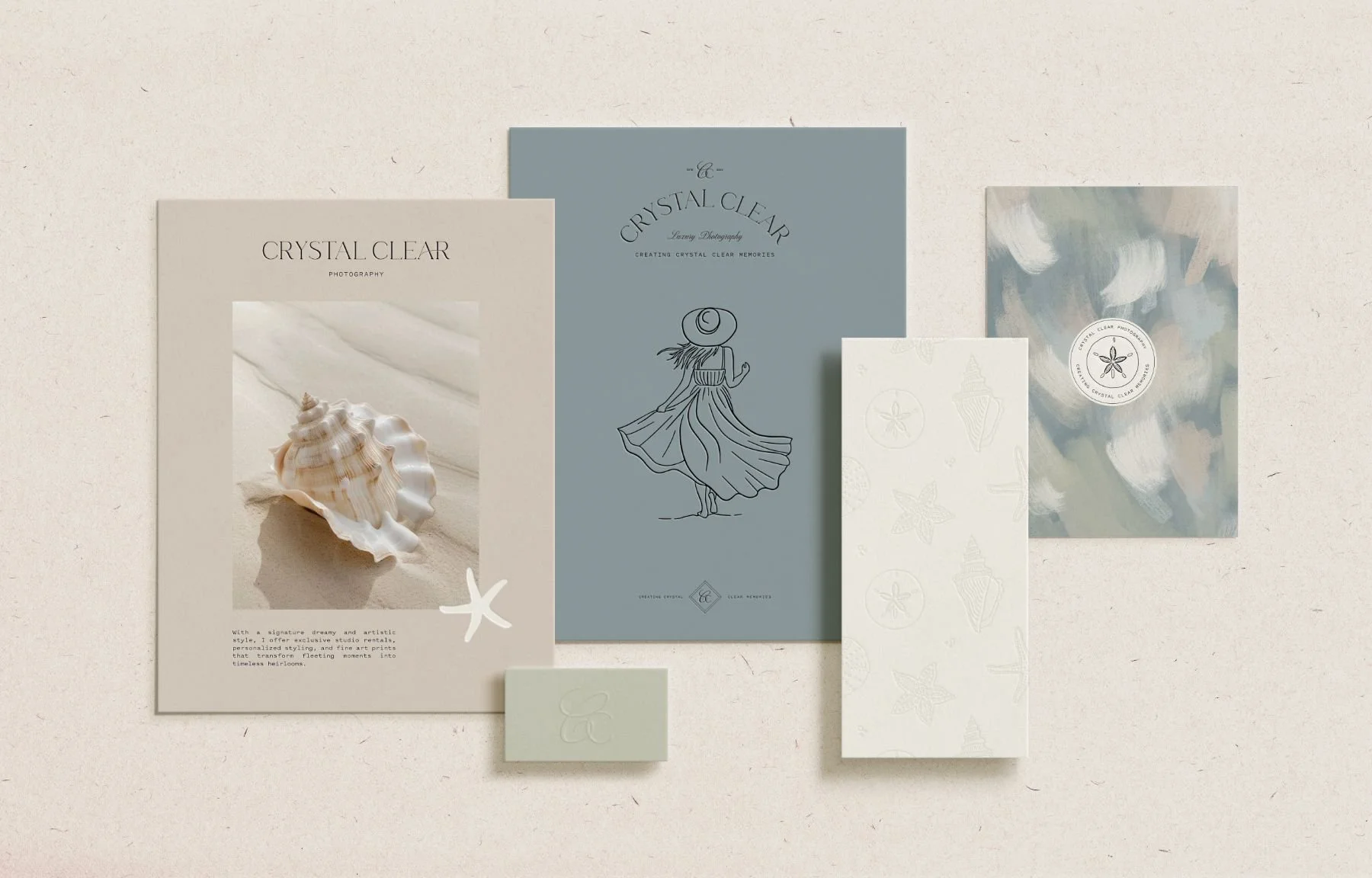 Various paper stationery items with beach and marine motifs, including a shell, starfish, and abstract watercolor designs on textured backgrounds.