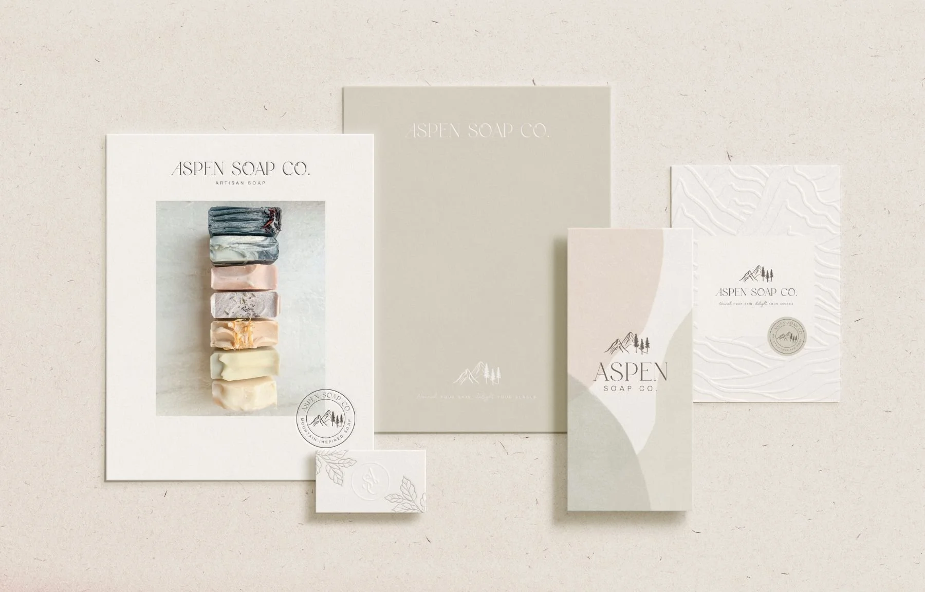 Various packaging materials and soap bars from Aspen Soap Co. displayed on a beige surface.