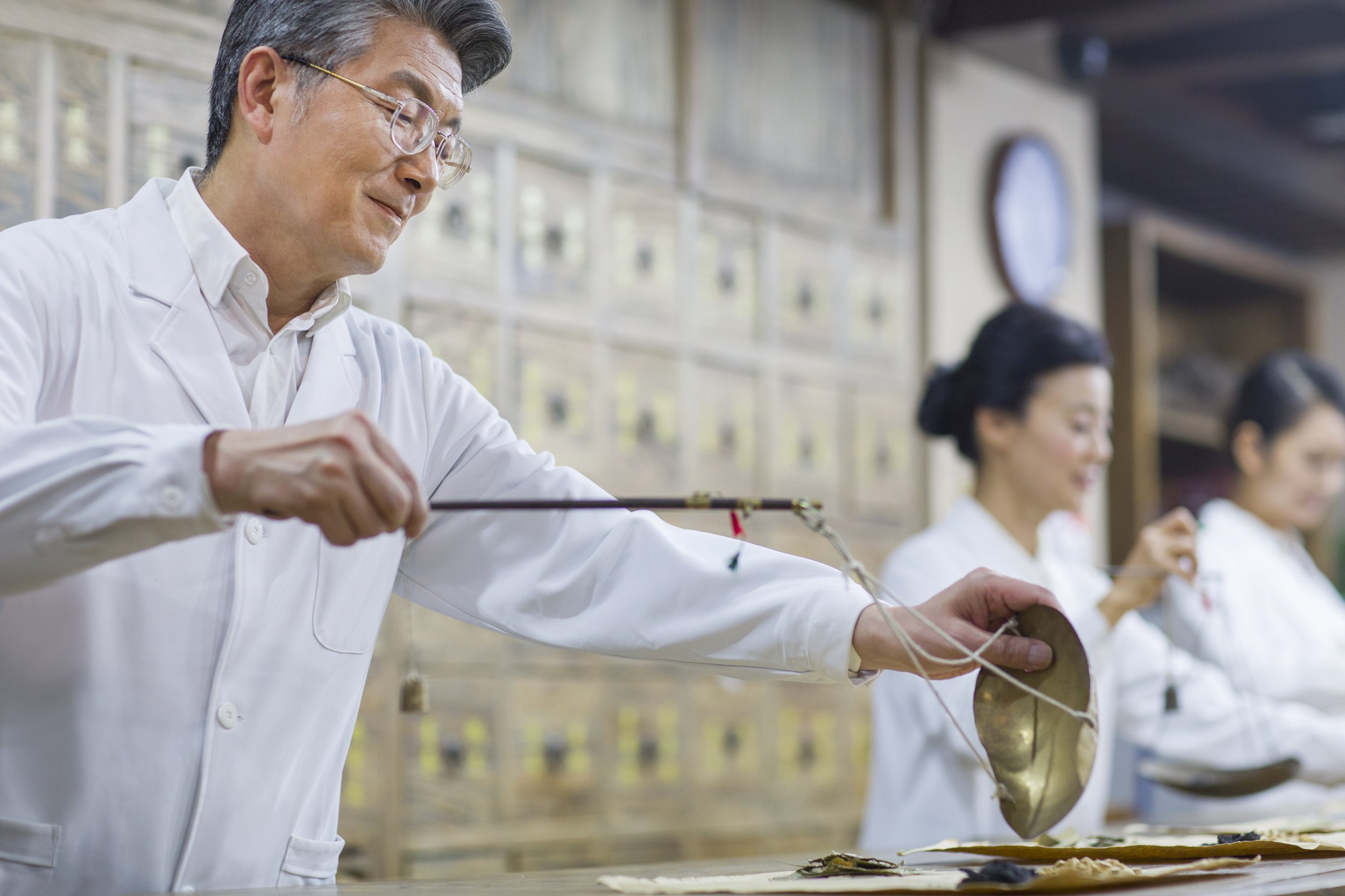 TCM therapy in Singapore with a traditional Chinese medicine practitioner preparing herbal treatment using classical techniques in a clinical setting