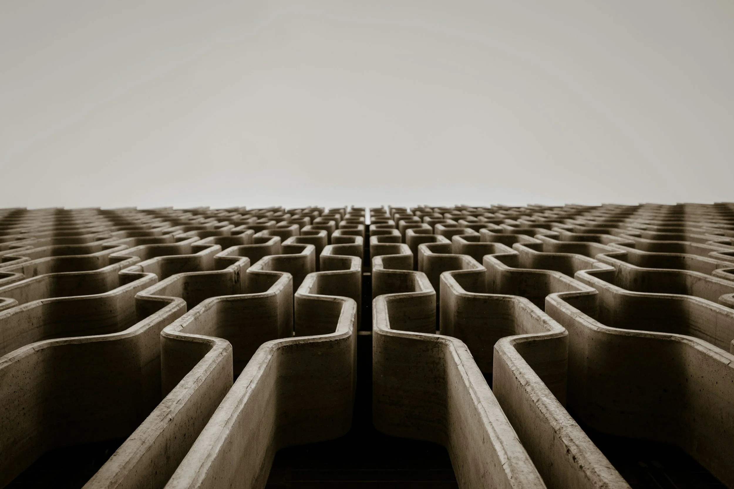 Close-up of a concrete structure with repeating rectangular voids, looking upward toward the sky.