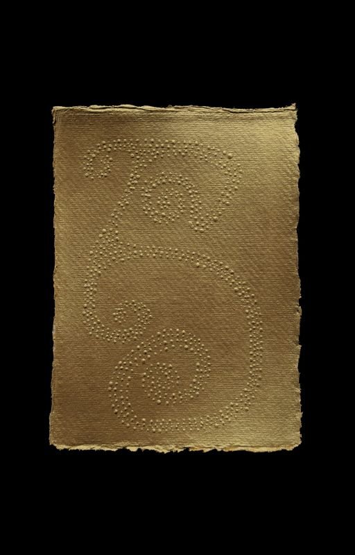 A piece of beige paper with a decorative swirl design made of small raised dots on a black background.
