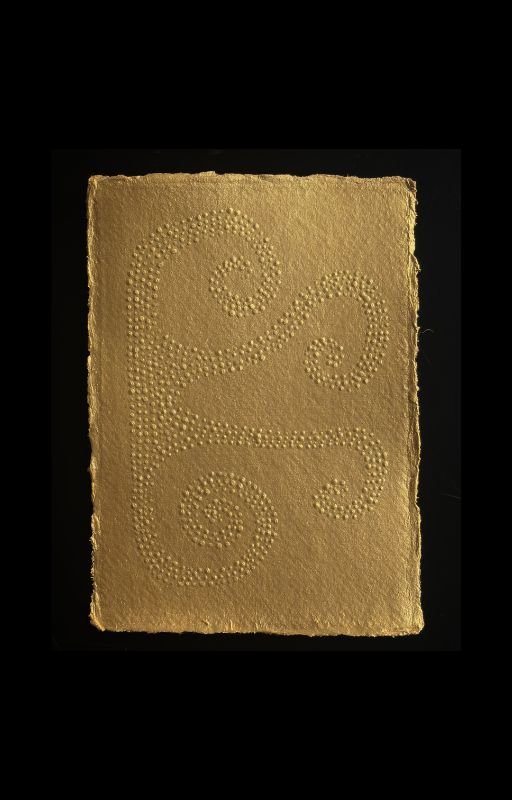 A gold-colored notebook with embossed swirling patterns on the cover, set against a black background.