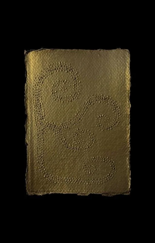 A rectangular gold-colored surface with embossed swirl patterns, set against a black background.
