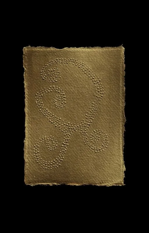 A piece of textured, tan paper with decorative swirl patterns made of small raised dots.