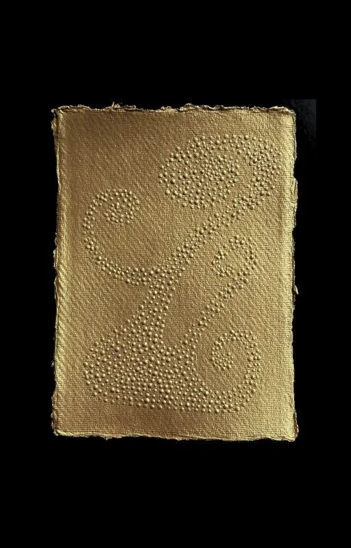A beige rectangular textured card with an ampersand '&' symbol created by small raised dots.