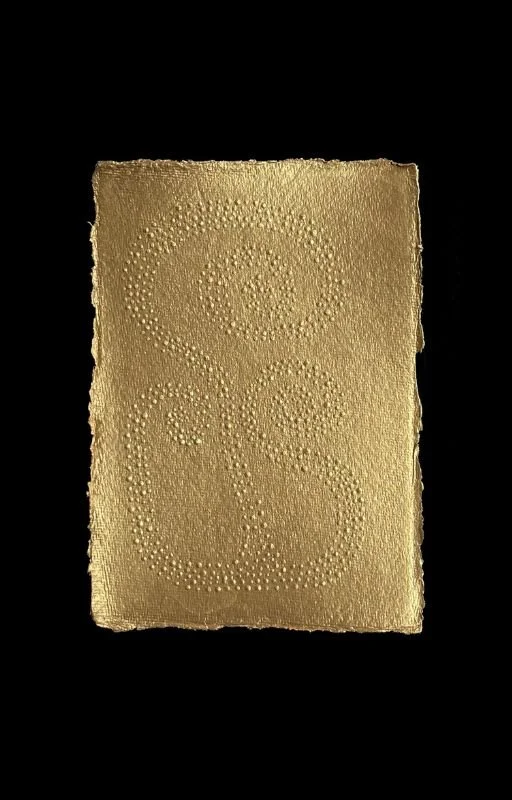 A rectangular sheet of gold-colored edible paper with embossed circular patterns, on a black background.