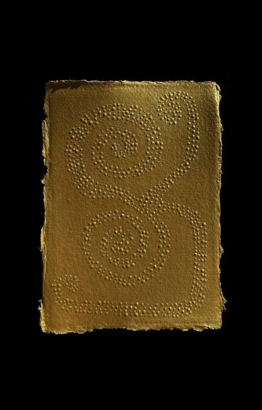 Piece of yellow-colored paper with a heart-shaped pattern made of small raised dots.