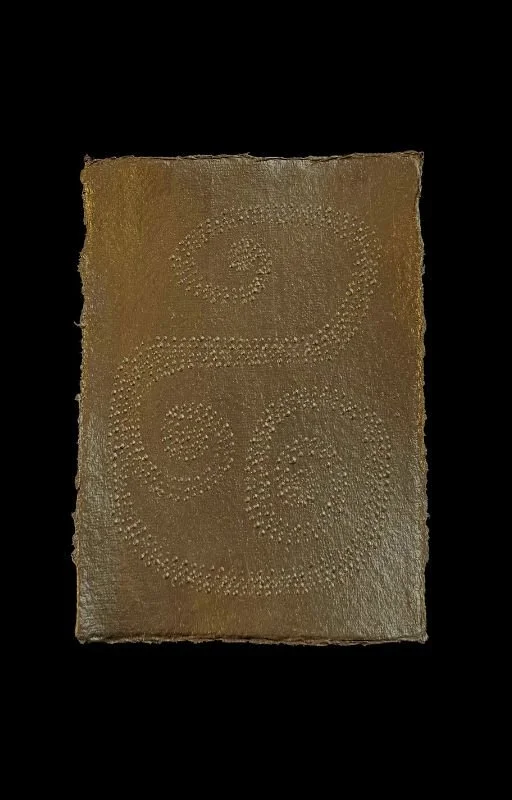 A rectangular sheet of chocolate with a decorative swirl pattern made of small dots.