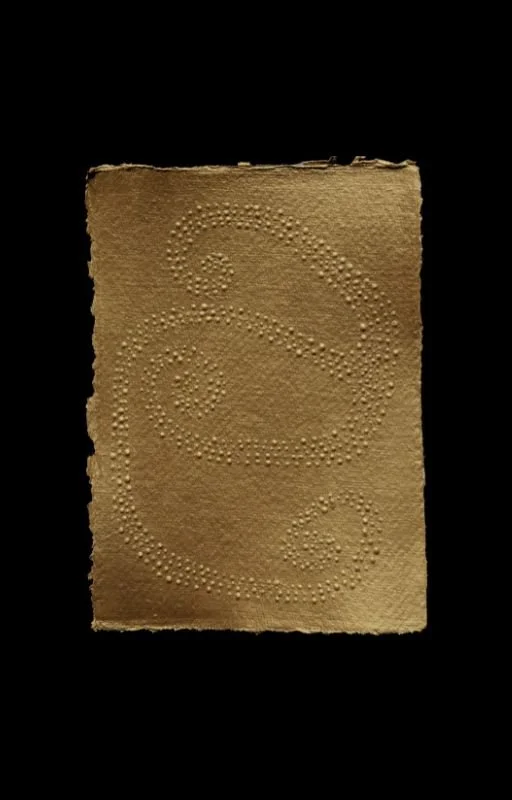 Sandpaper sheet with tiny bumps arranged to form a stylized letter 'A'.