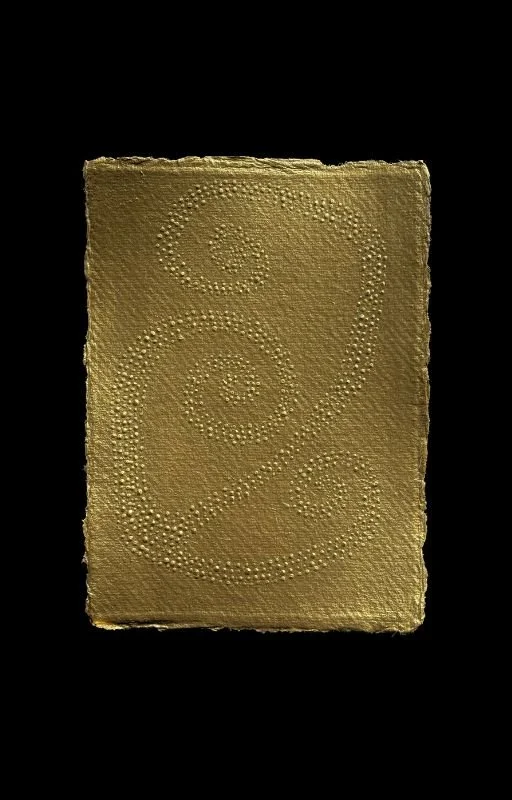 Decorative gold-colored card with embossed swirling patterns on a black background.