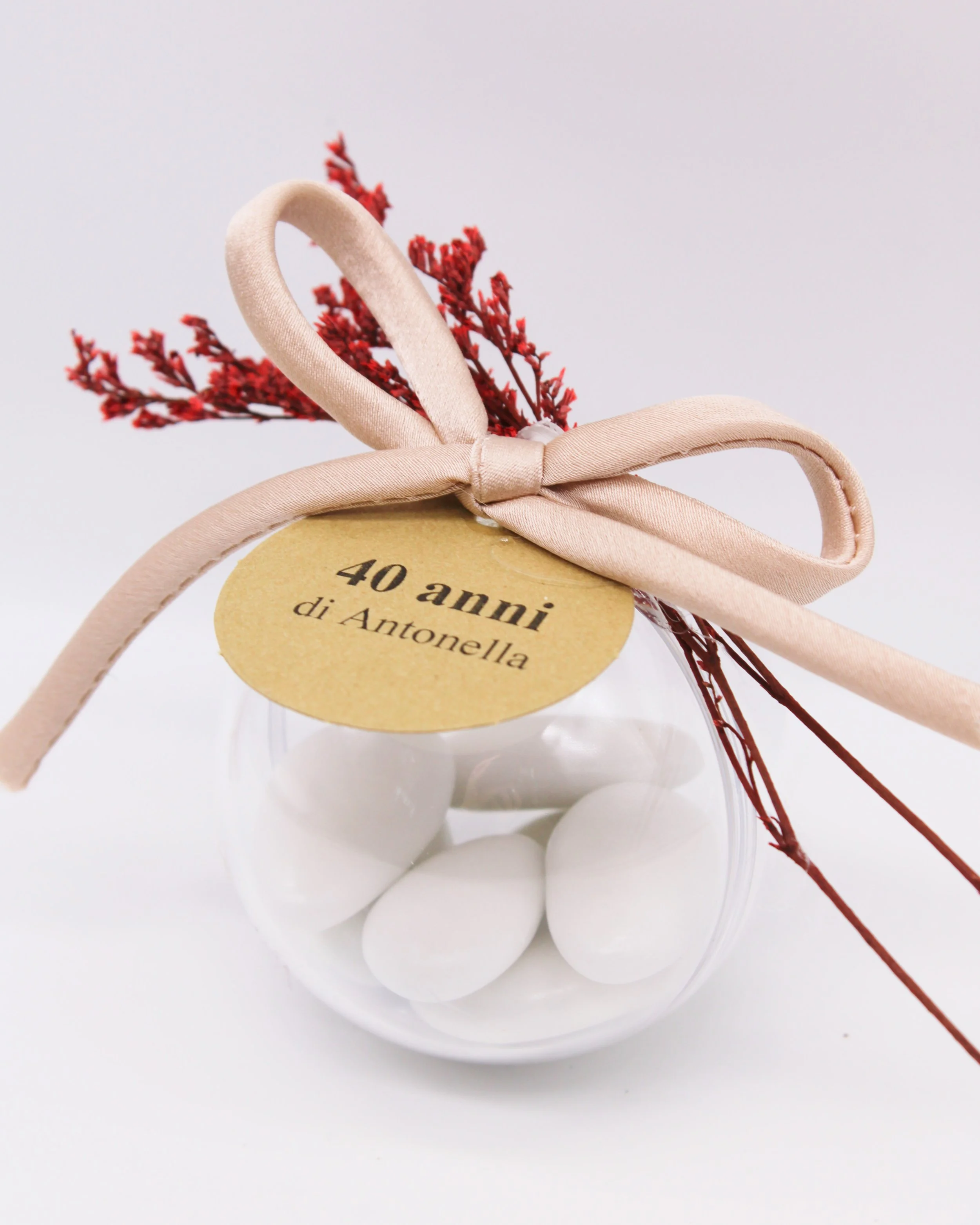 Scatola regalo bianca con fiocco di raso, bottiglia di cristallo trasparente con mappamondo inciso, sfondo bianco.