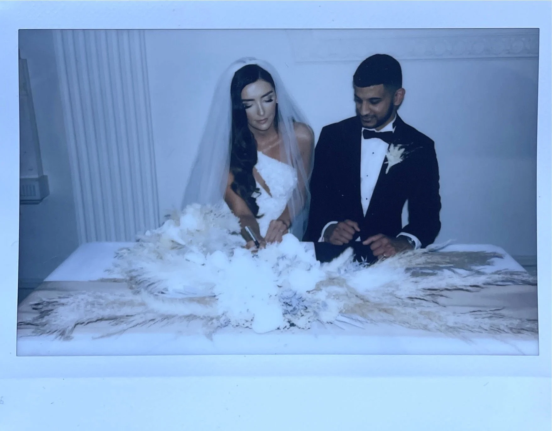 Bride and groom signing a wedding document at a decorated table.