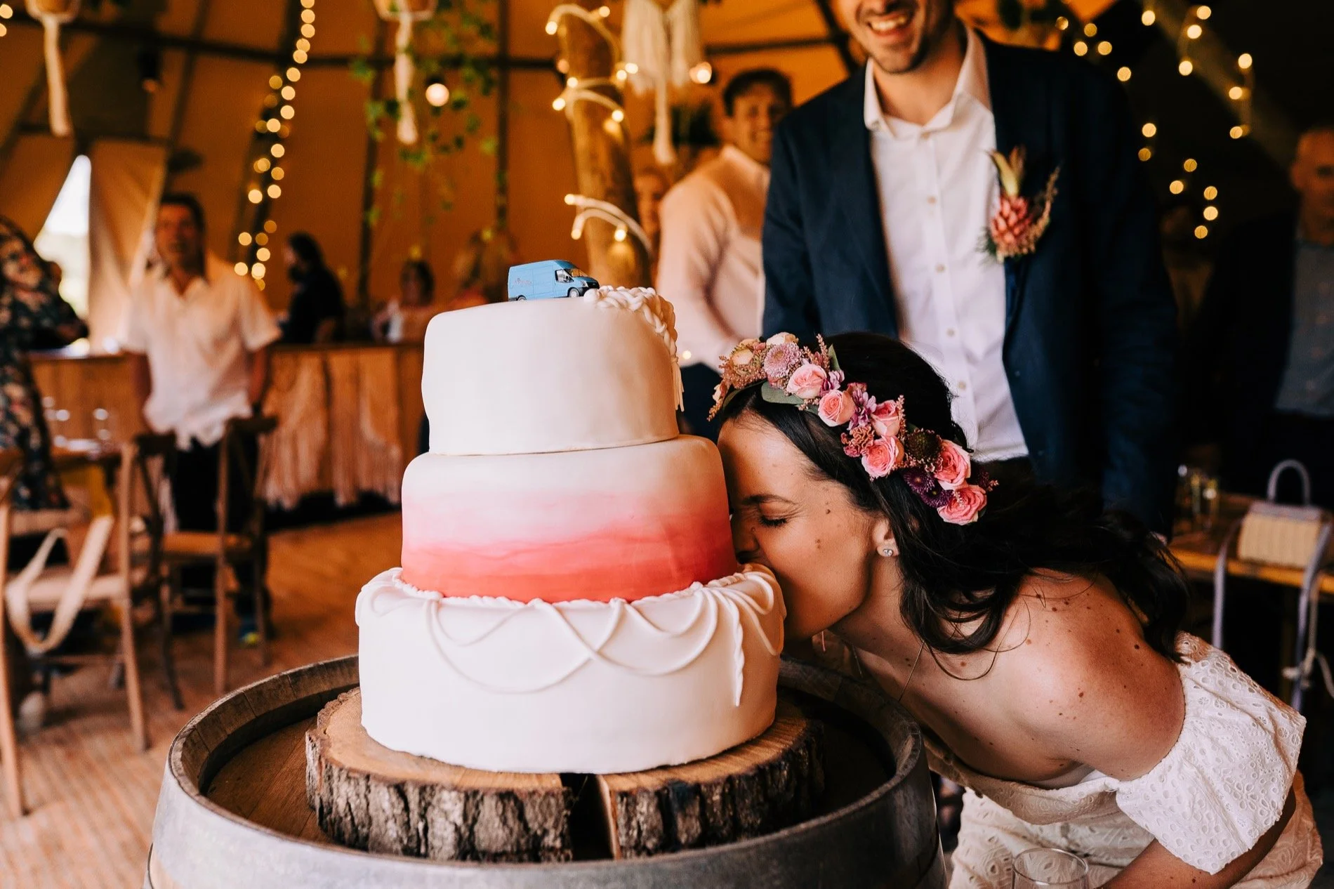 Bride bending down and biting into the bottom tier of wedding cake