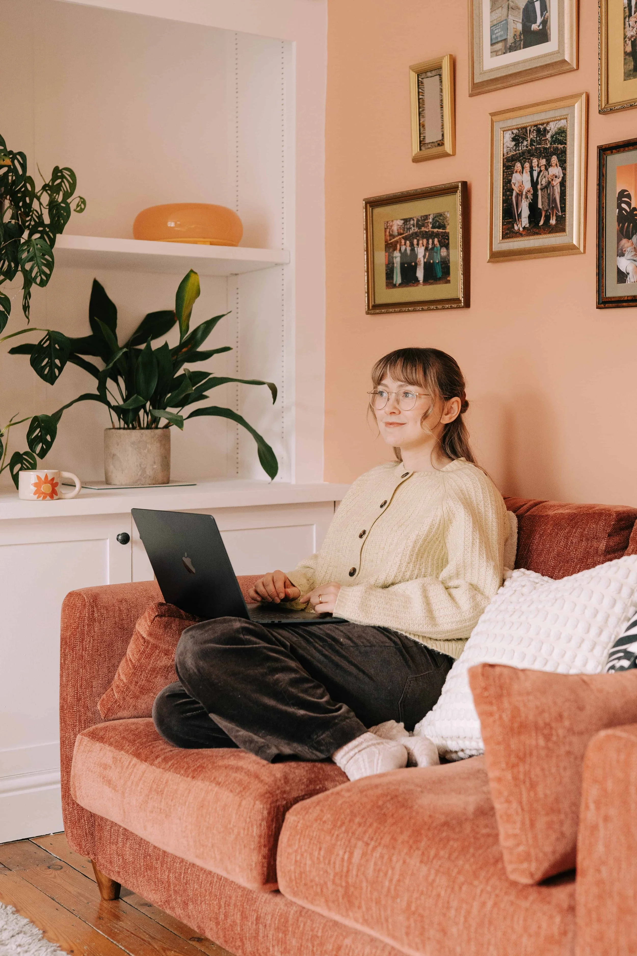 Lydia Draws sat in the sofa with her mac book doing admin