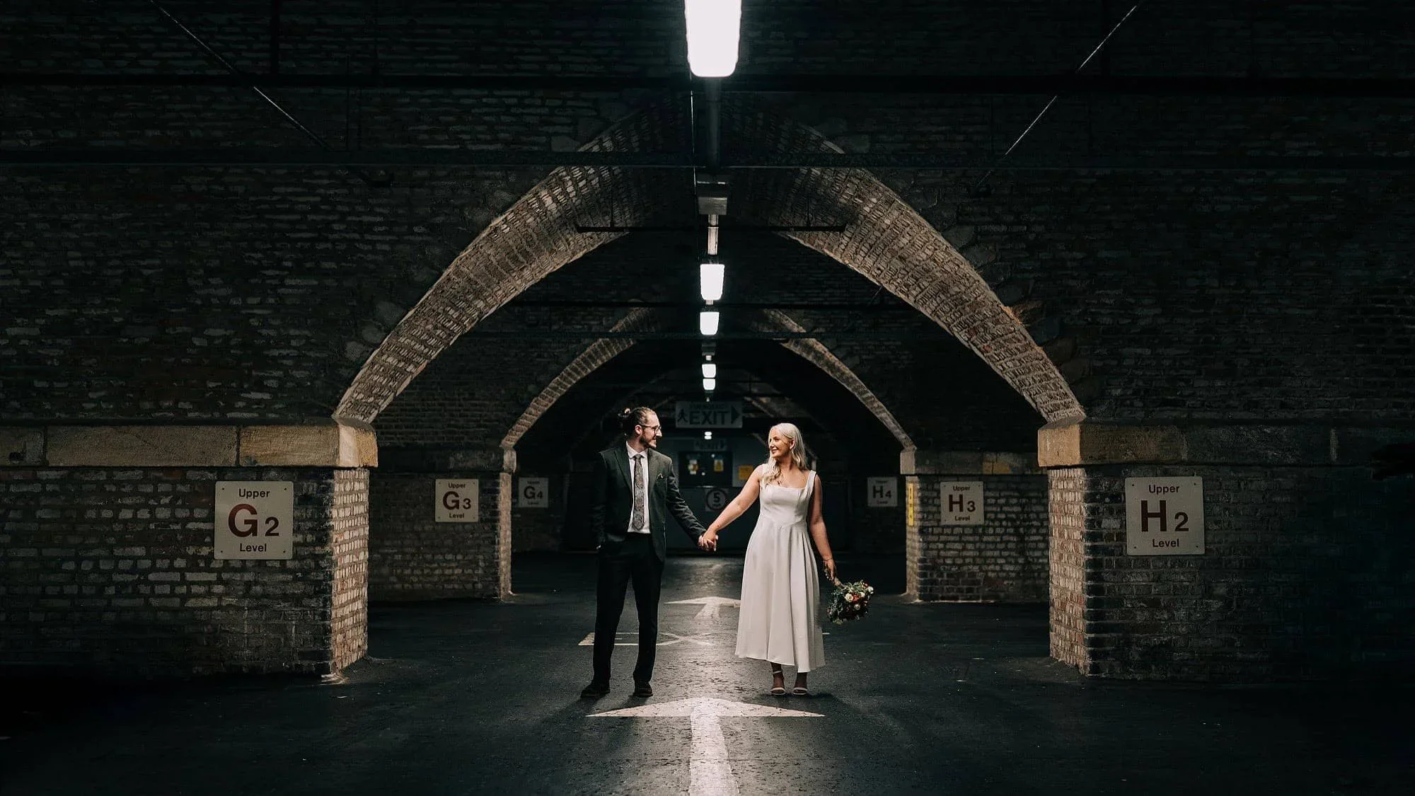 Wedding couple stood holding hands in underground manchester city centre carpark