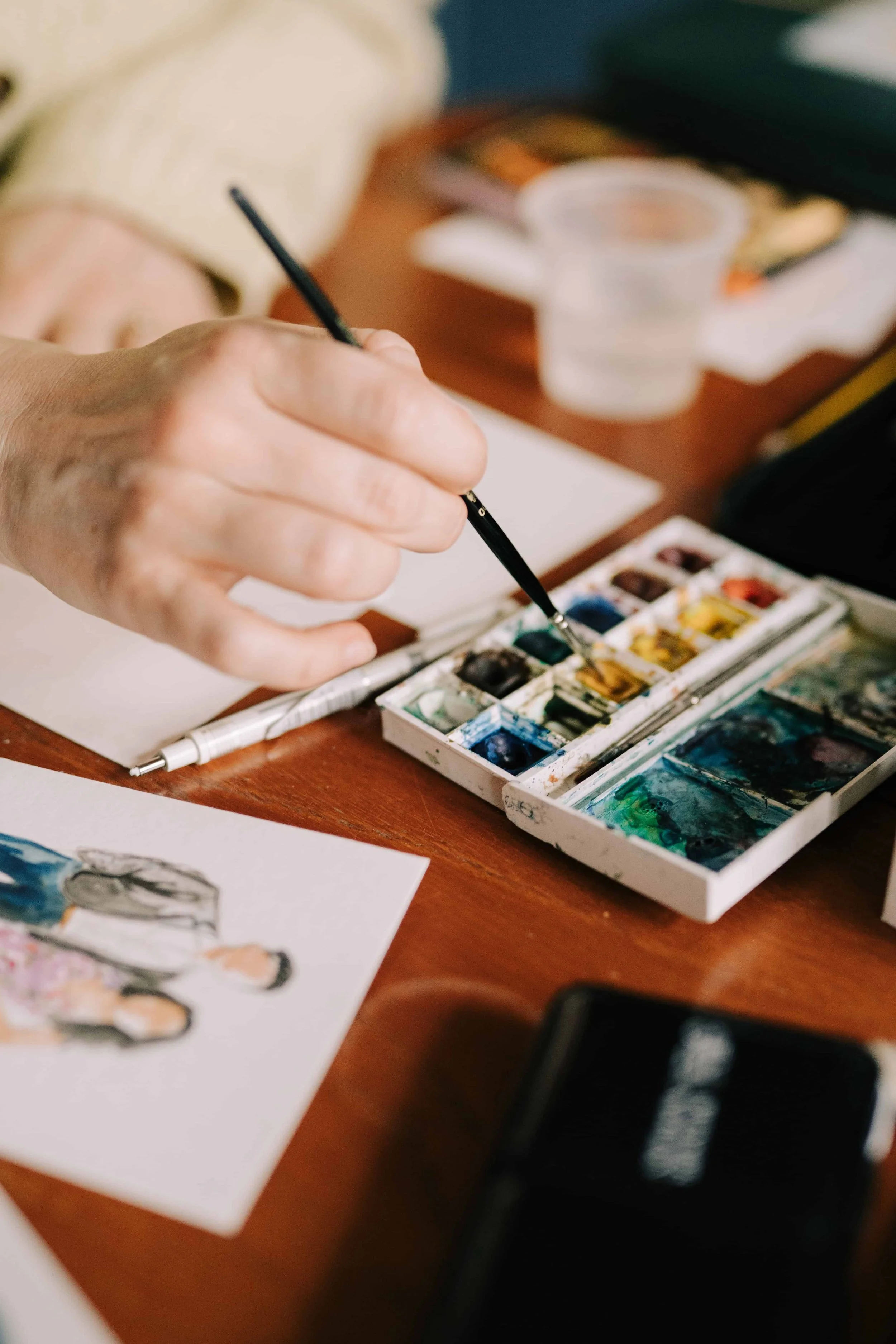 Lydia Draws hand holding a paint brush in watercolour