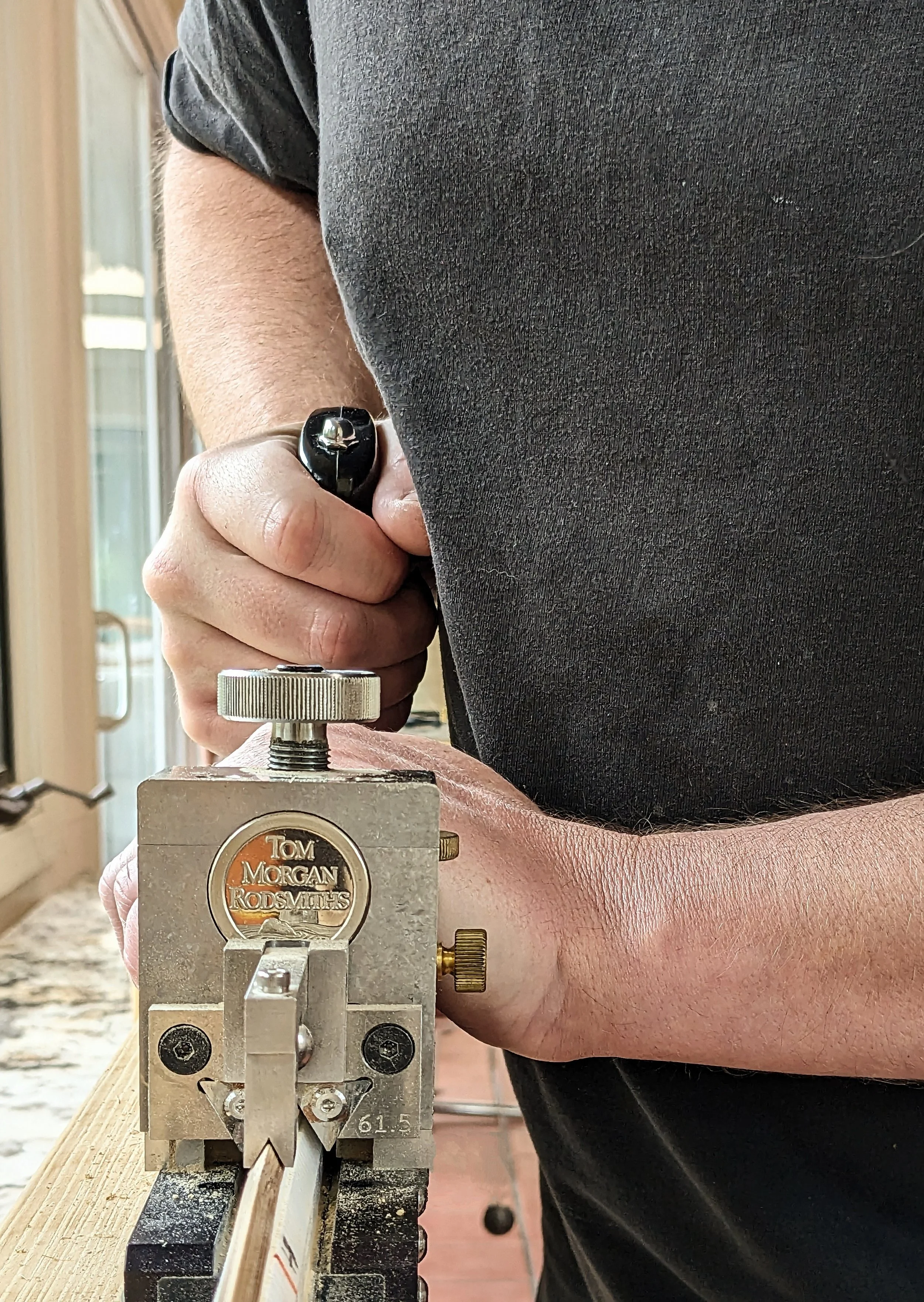 Man pushing specialized hand plane to mill bamboo rod section strip