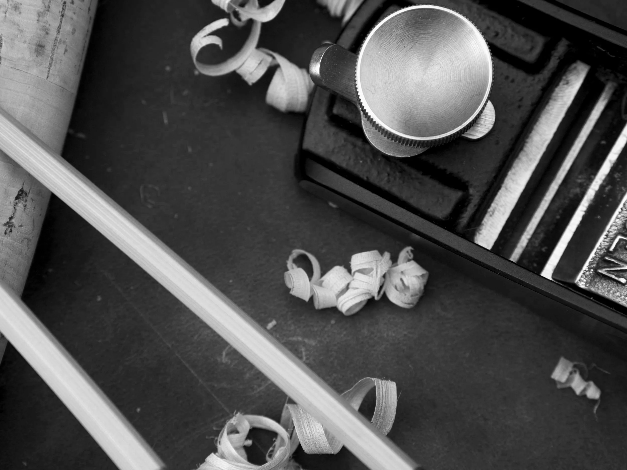 Black and white image of hand plane with bamboo shavings and rod section.