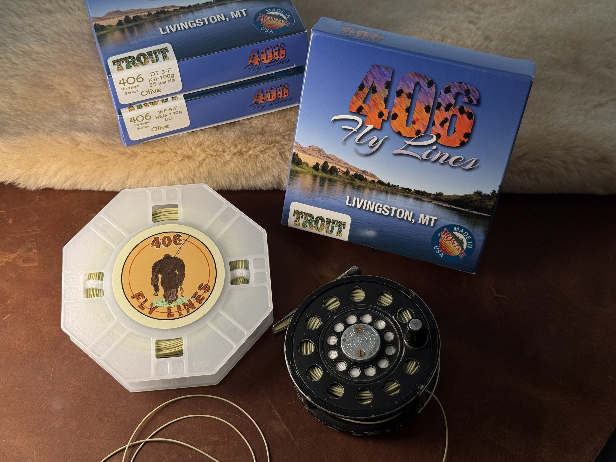 boxes of fly lines and a fly reel sitting on shearling and leather. (Copy)