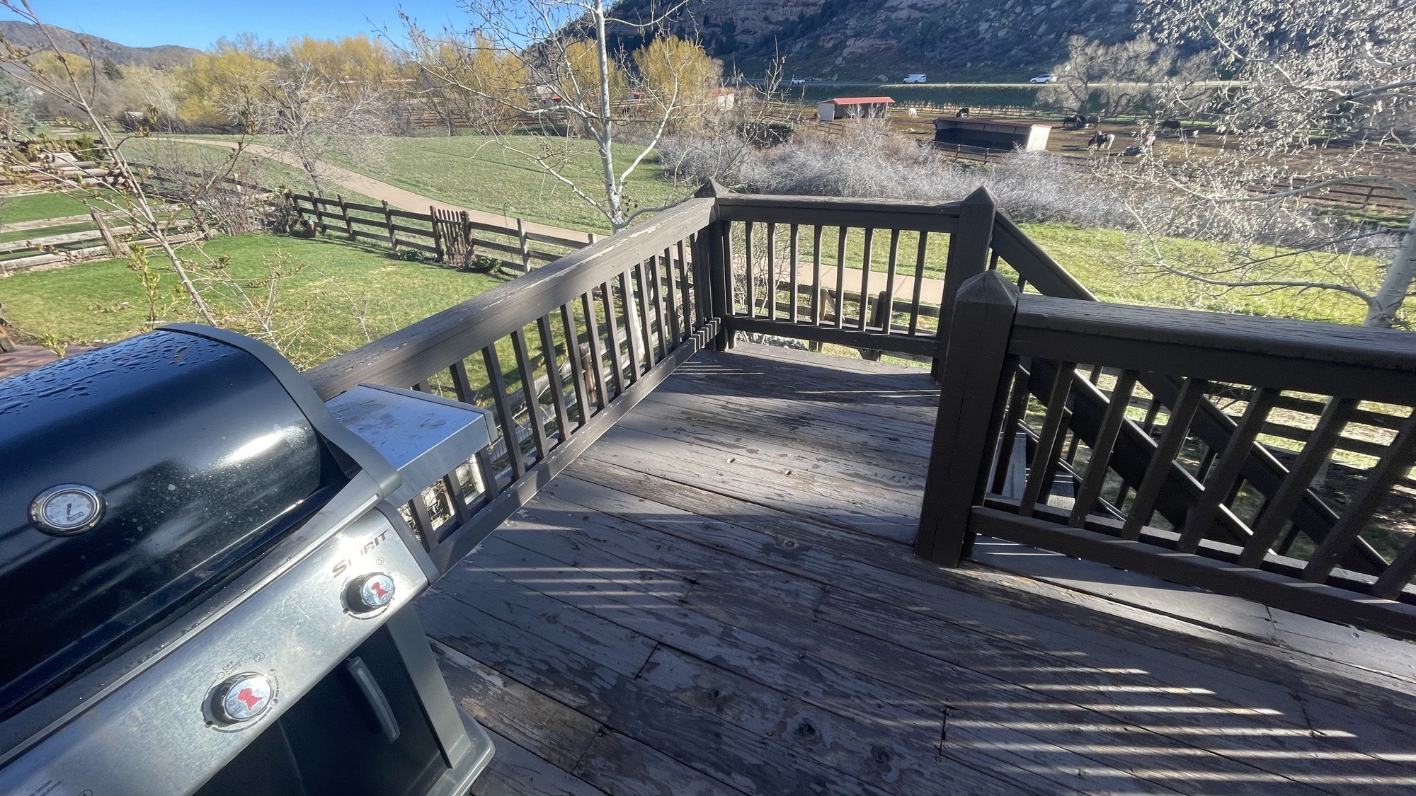 Weathered, greying wood deck boards showing UV and freeze-thaw wear at a Colorado home