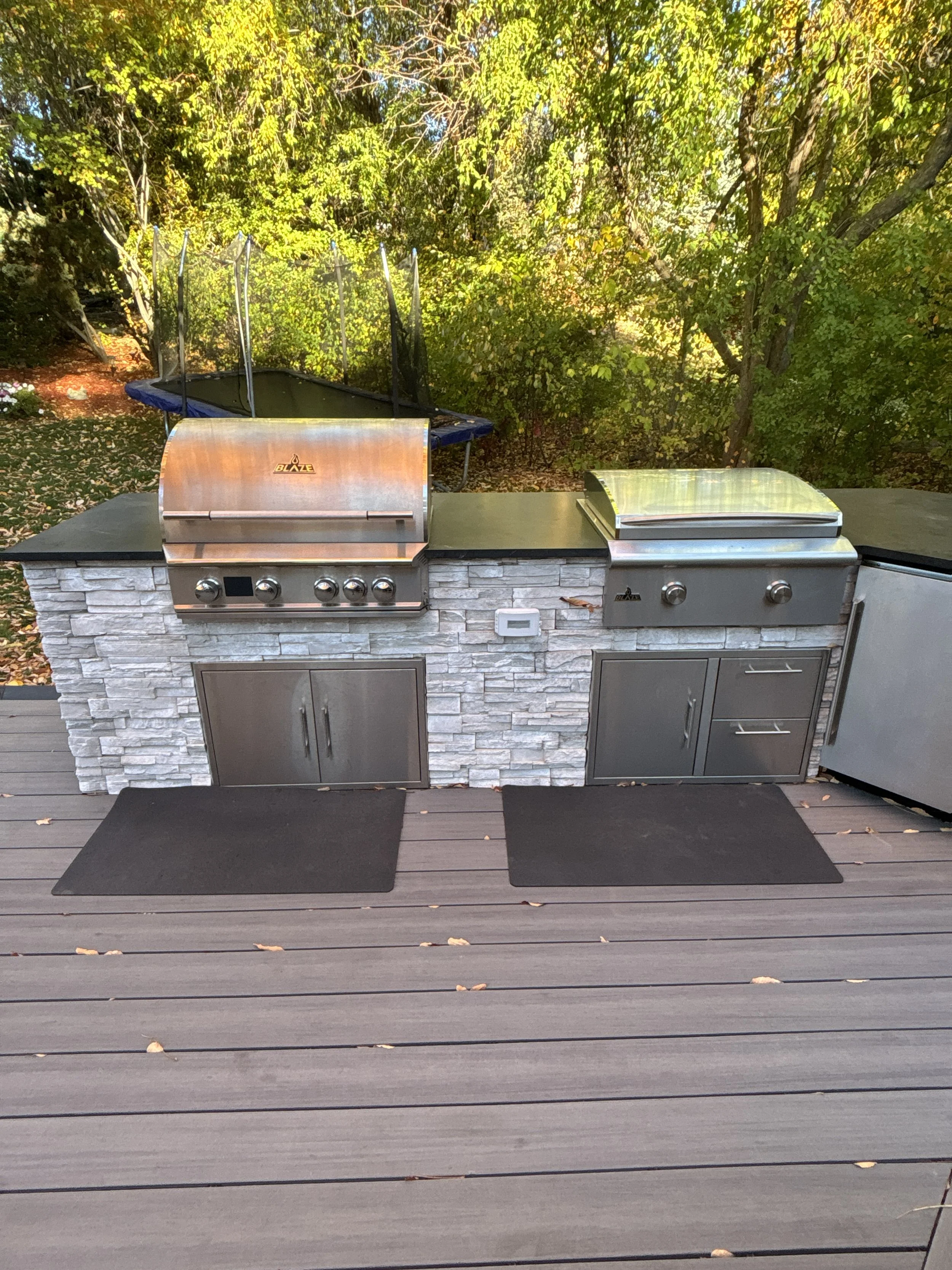 Built-in Blaze grill and griddle with stone base on a composite deck.