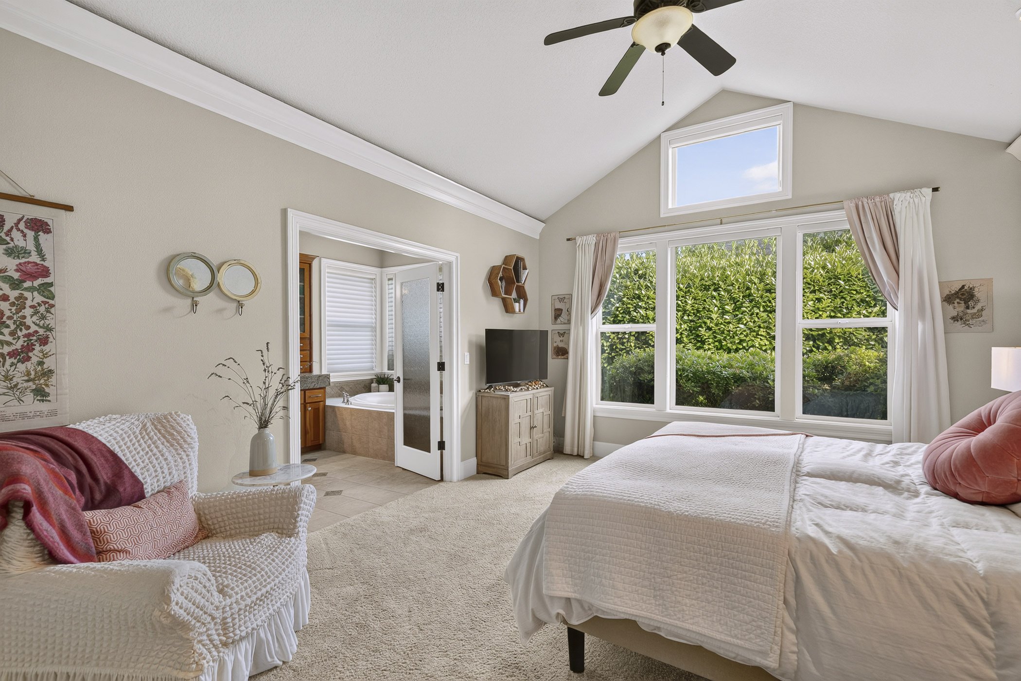 Primary bedroom with french doors leading into a luxurious primary bathroom