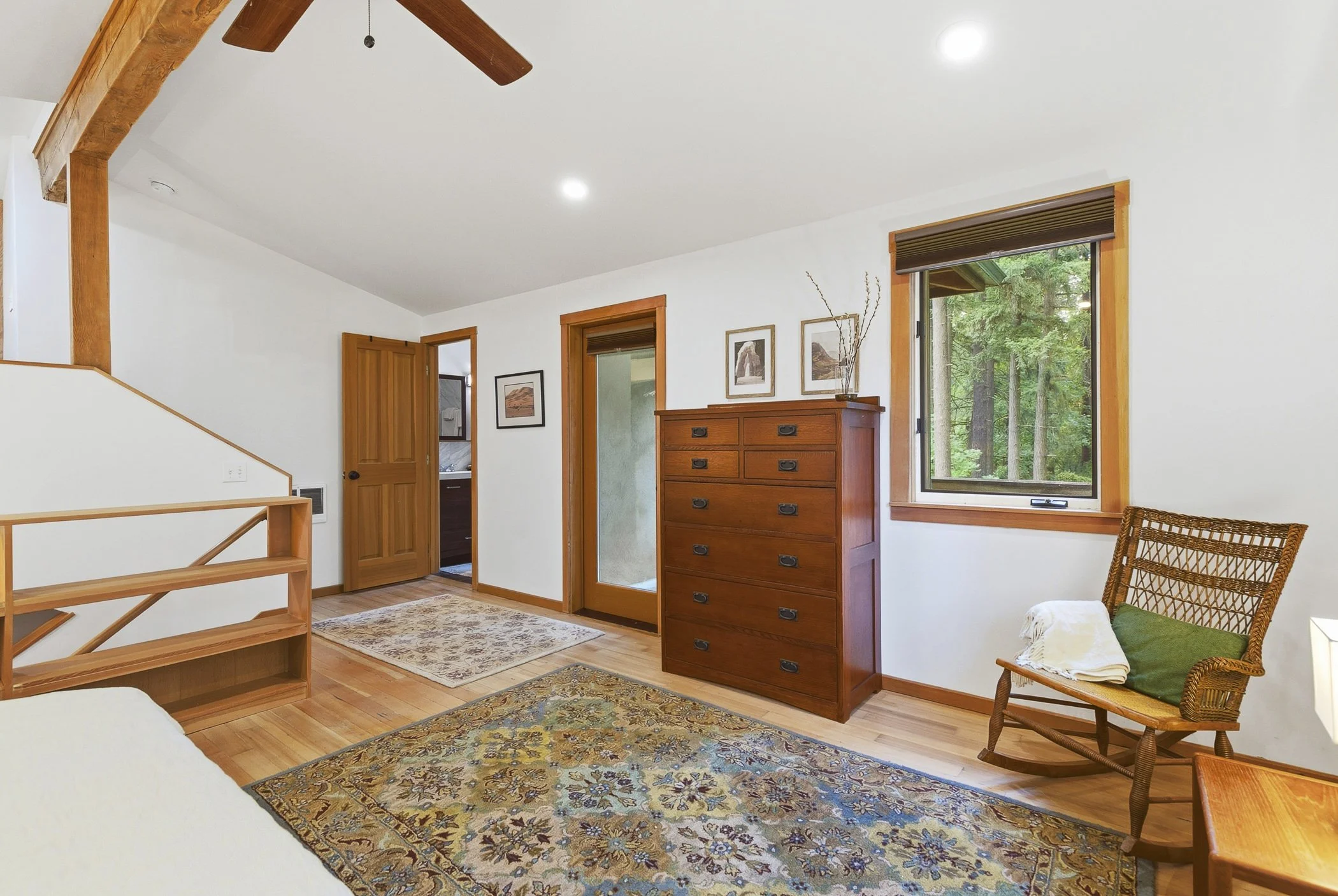 View overlooking a bed to show the location of the primary bathroom and door access to the deck area in SW Portland