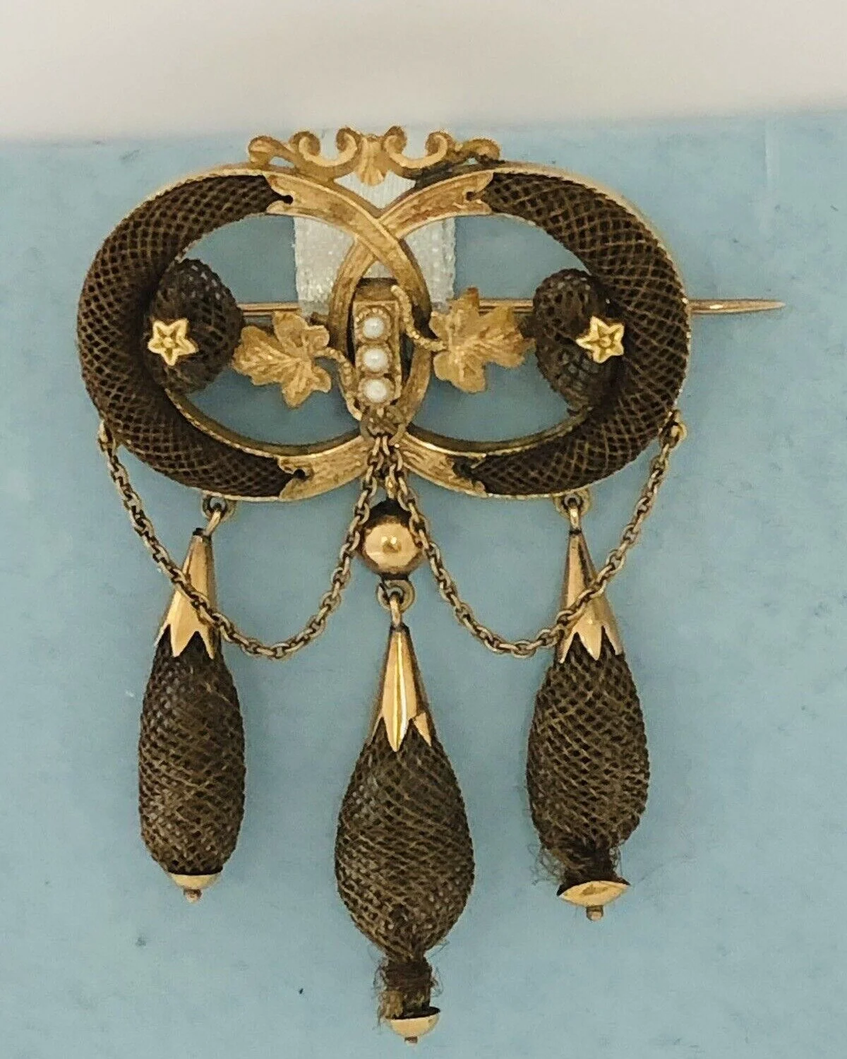 Welcome to Thursday! We are delighted to share another hair worked item of antiquity with you!

  This is an amazing table braided human hair brooch set in 14 karat gold findings with seed pearls. In the center we see 3 seed pearls that are flanked w